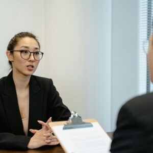 A focused interview scene in an office environment with business attire and a clipboard.